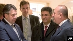 FILE - German Foreign Minister Sigmar Gabriel, left, talks to his Turkish counterpart Mevlut Cavusoglu, right, after a meeting in a hotel in Berlin, March 8, 2017. 