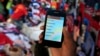 A man holds up his mobile phone showing an M-Pesa mobile money transaction page at an open-air market in Kibera in Kenya's capital, Nairobi, Dec. 31, 2014.