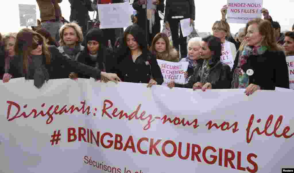 Former French first ladies Carla Bruni-Sarkozy (left) and Valerie Trierweiler (right) stand with politicians and entertainment artists holding a banner that reads "Leaders, bring back our girls" during a demonstration near the Eiffel Tower in Paris, May 13, 2014.