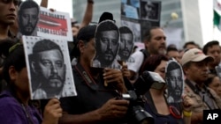 Manifestantes portan fotos de Ruben Espinosa, periodista asesinado en México durante una protesta el domingo, 2 de agosto de 2015.