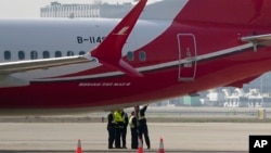 Ground crew members chat near a Boeing 737 MAX 8 plane operated by Shanghai Airlines parked on tarmac at Hongqiao airport in Shanghai, China, March 12, 2019. 
