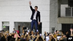 FILE - Opposition leader Juan Guaido waves to supporters during a rally at Bolivar Plaza in Chacao, Venezuela, Feb. 11, 2020. Guaido returned home from a tour of nations that back his effort to oust socialist leader Nicolas Maduro.