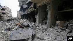 FILE - People inspect a damaged site after airstrikes on the town of Ariha, in Idlib Province, Syria, Jan. 30, 2020.