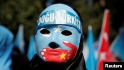 Seorang pengunjuk rasa Uighur mengenakan topeng dalam unjuk rasa di depan Konsulat China di Istanbul, Turki, 1 Oktober 2019.