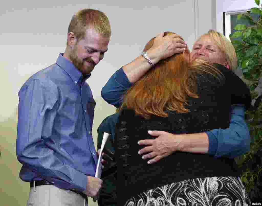 Kevin Brantly (left), who contracted the deadly Ebola virus, looks down as his wife Amber (center) hugs a member of Emory's medical staff during a press conference at Emory University Hospital in Atlanta, Georgia, Aug. 21, 2014.