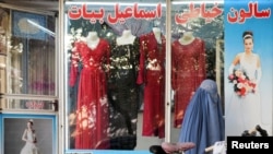 Seorang perempuan mengenakan burqa, berjalan melewati toko pakian perempuan dengan patung peraga (mannequin) tanpa kepala yang dipajang di etalase toko tersebut di Kabul, Afghanistan, 19 Oktober 2021. (REUTERS/Zohra Bensemra)