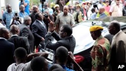 Zimbabwe President Emmerson Mnangagwa, center, leaves after paying his respects to the family of Morgan Tsvangirai, in Harare, Feb. 18, 2018.
