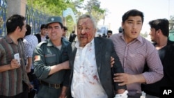 A wounded man is assisted after gunmen stormed a courthouse in Mazar-i-Sharif, north of Kabul, Afghanistan, April, 9, 2015. 