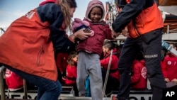 A migrant child is helped from the Spanish NGO Proactiva Open Arms rescue vessel, after being rescued Dec. 21, in the Central Mediterranean Sea, to disembark in the port of Crinavis in Algeciras, Spain, Dec. 28, 2018.