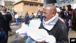 Mkazi wa Libya akiwa amebeba mabaki ya mwili wa mtu mmoja kwenye hospitali ya Al-Jalaa huko Benghazi, mji wa pili kwa ukubwa nchini Libya siku ya Jumatatu.