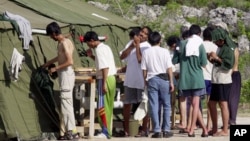 FILE - Men shave, brush their teeth and prepare for the day at a refugee camp on the Island of Nauru, Sept. 21, 2001.