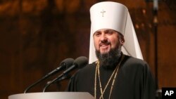A new head of independent Ukrainian church Metropolitan of Kiev Epiphanius greets people gathered to support independent Ukrainian church near the St. Sophia Cathedral in Kyiv, Dec. 15, 2018. 