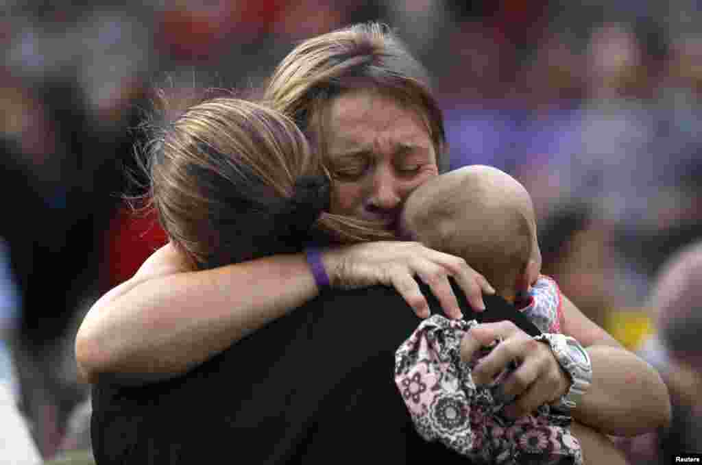 A woman holding a baby hugs another person seated in the section reserved for immediate family of the 19 firefighters killed in a nearby wildfire in Prescott, Arizona, USA, July 2, 2013.