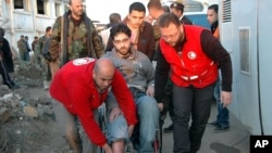 Syrian Arab Red Crescent members in red uniforms help evacuate injured man on a bus out of the battleground city of Homs. This photo was released by the official Syrian news agency.