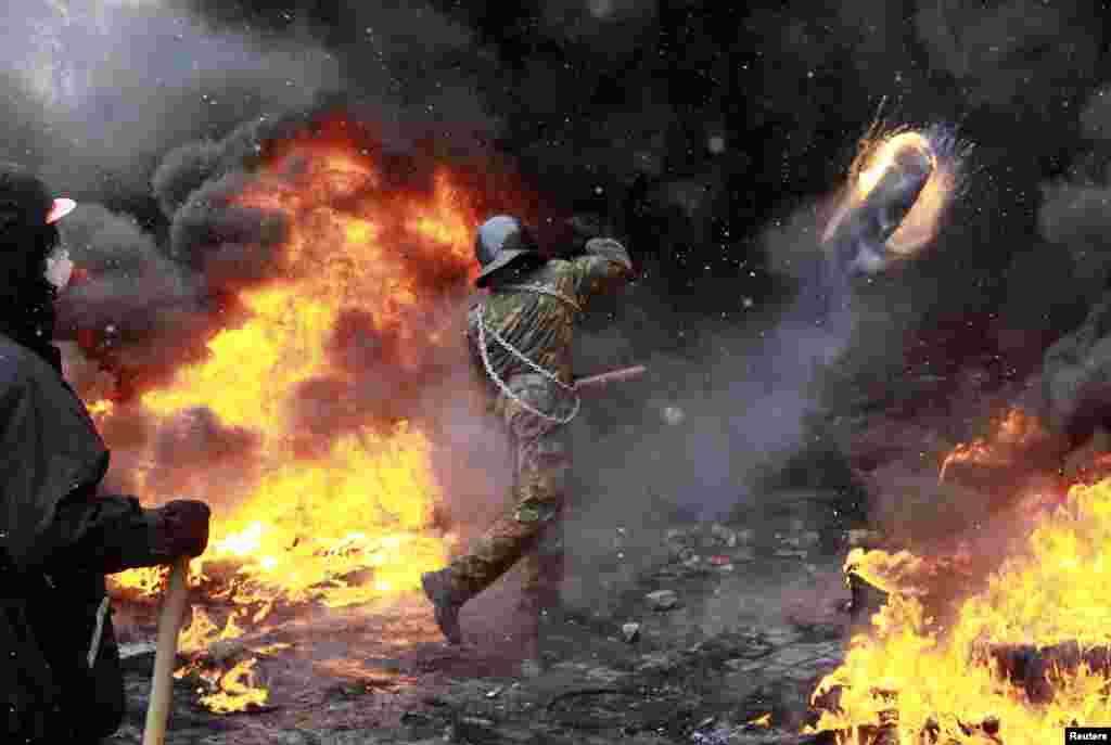 A pro-European protester throws a burning tire during clashes with riot policemen in Kyiv. The European Union threatened to take action against Ukraine over its handling of anti-government protests after three people died during violent clashes in the capital.