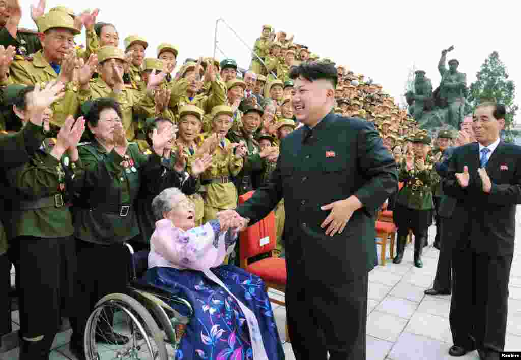 Pemimpin Korea Utara Kim Jong-Un tertawa selama sesi foto di Pyongyang dengan para veteran perang dalam perayaan ulang tahun ke-60 berakhirnya Perang Korea.