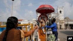 A Sri Lankan navy officer helps a Catholic devotee offer a garland outside St. Anthony's Church, one of the targets of Easter Sunday attacks in Colombo, Sri Lanka, May 5, 2019. 