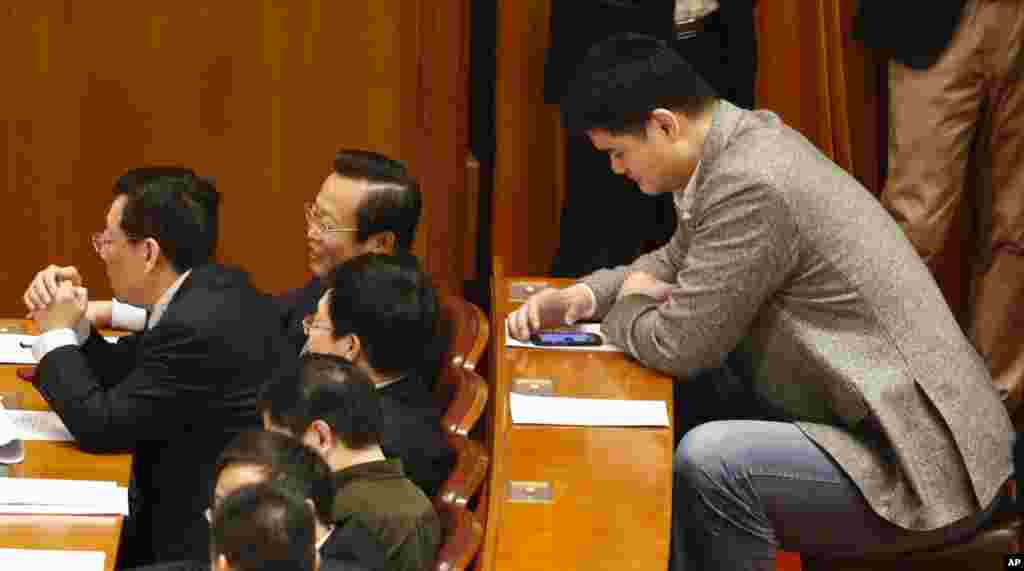 Yao Ming, former NBA basketball star and a delegate to the Chinese People's Political Consultative Conference, looks at his phone during the closing ceremony of the CPPCC in Beijing's Great Hall of the People, China.