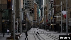 People in protective face masks walk through the quiet city center during a lockdown to curb the spread of COVID-19 outbreak in Sydney, Australia, July 28, 2021.