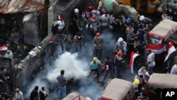 An anti-government protester prepares to throw a tear gas canister fired by Iraq security forces to disperse a crowd during a demonstration, in Baghdad, Iraq, Oct. 30, 2019. 