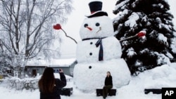 ARCHIVO - Isil Mico toma una foto de su cuñada Oznur Mico delante de Snowzilla, un muñeco de nieve de más de 6 metros de altura, en Anchorage, Alaska, el 10 de enero de 2024. 