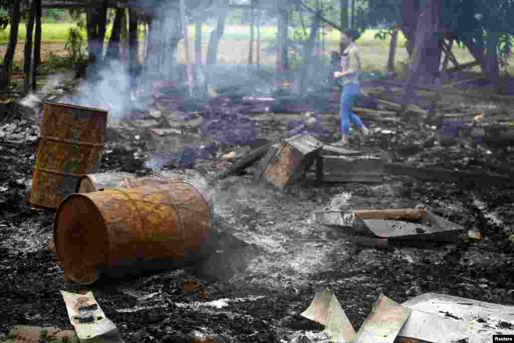 A journalist walks amongst the remains of houses at Shwe Lay village, outside of Thandwe in Rakhine state, western Burma, Oct. 2, 2013.