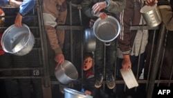 Warga Palestina berkumpul untuk menerima bantuan makanan yang didistribusikan di sepanjang pinggir jalan di kamp pengungsi Nuseirat di Jalur Gaza bagian tengah pada 11 Januari 2025, saat perang antara Israel dan militan Hamas terus berlanjut. (Foto: AFP)