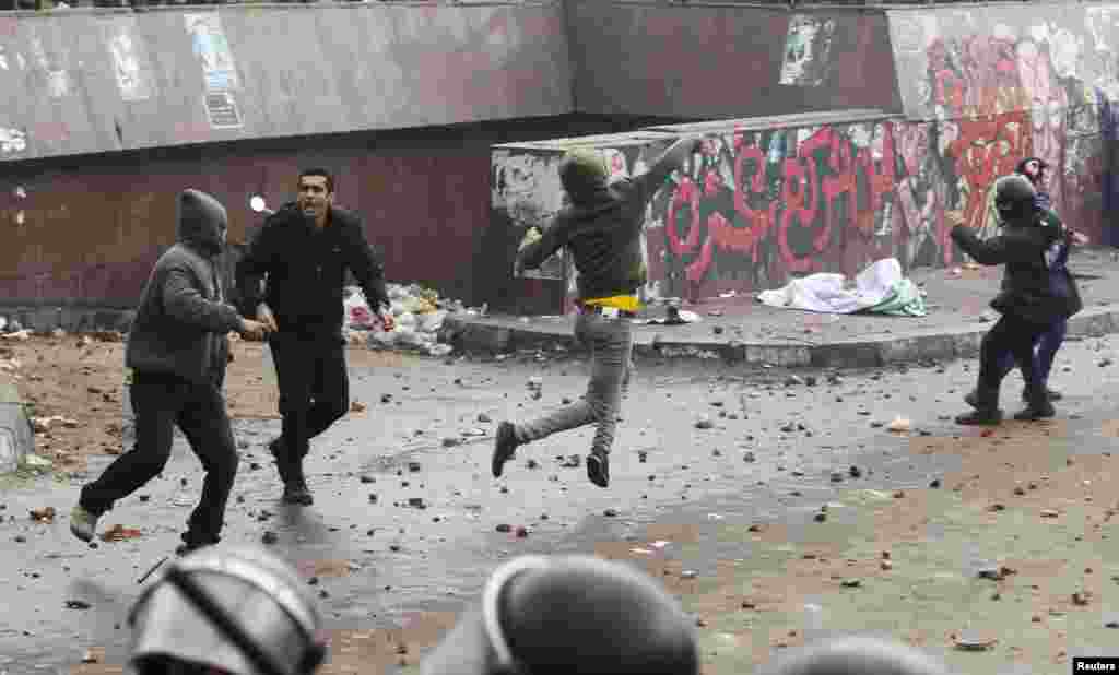 Riot police try to prevent protesters supporting Egyptian President Mohamed Morsi from throwing rocks at anti-Morsi protesters during clashes in Alexandria, Egypt, December 21, 2012.