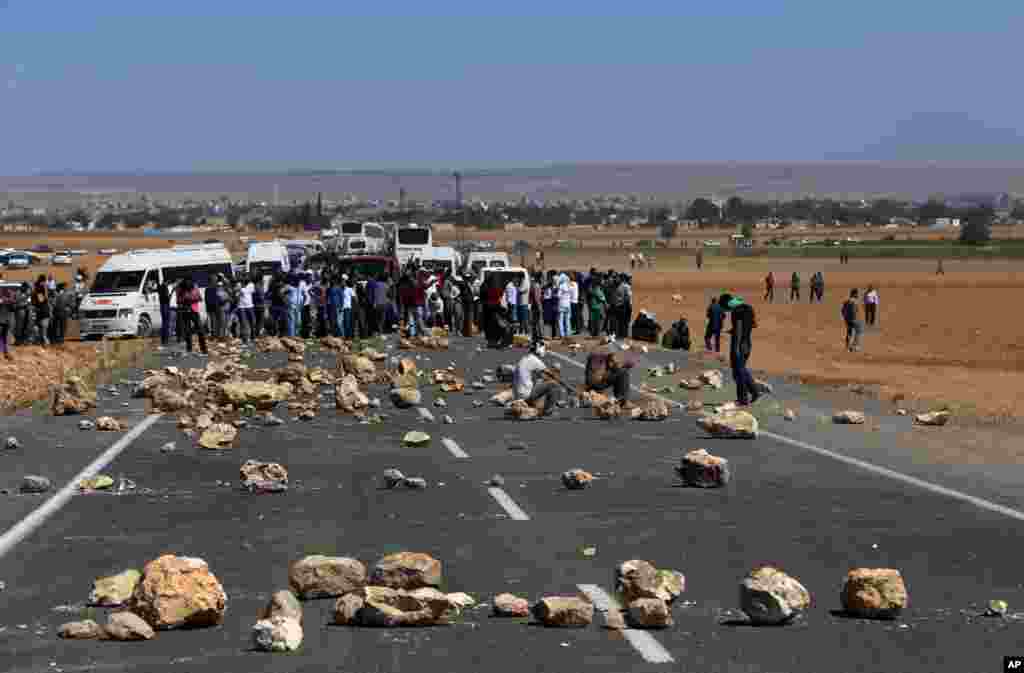 Demonstrators close a main road as several hundred Syrian refugees wait at the border in Suruc, Turkey, Sept. 21, 2014.