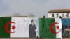 Des employés de la ville installe le drapeau algérien et un poster du président Abdelaziz Bouteflika, à Alger, en Algérie, le 26 avril 2016.