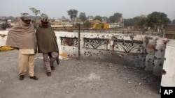 Indian villagers inspect the damage on the roof of a house, caused allegedly by firing from the Pakistan side of the border at Bainglad village in Samba sector, about 52 Kilometers from Jammu, India, Jan. 3, 2015.