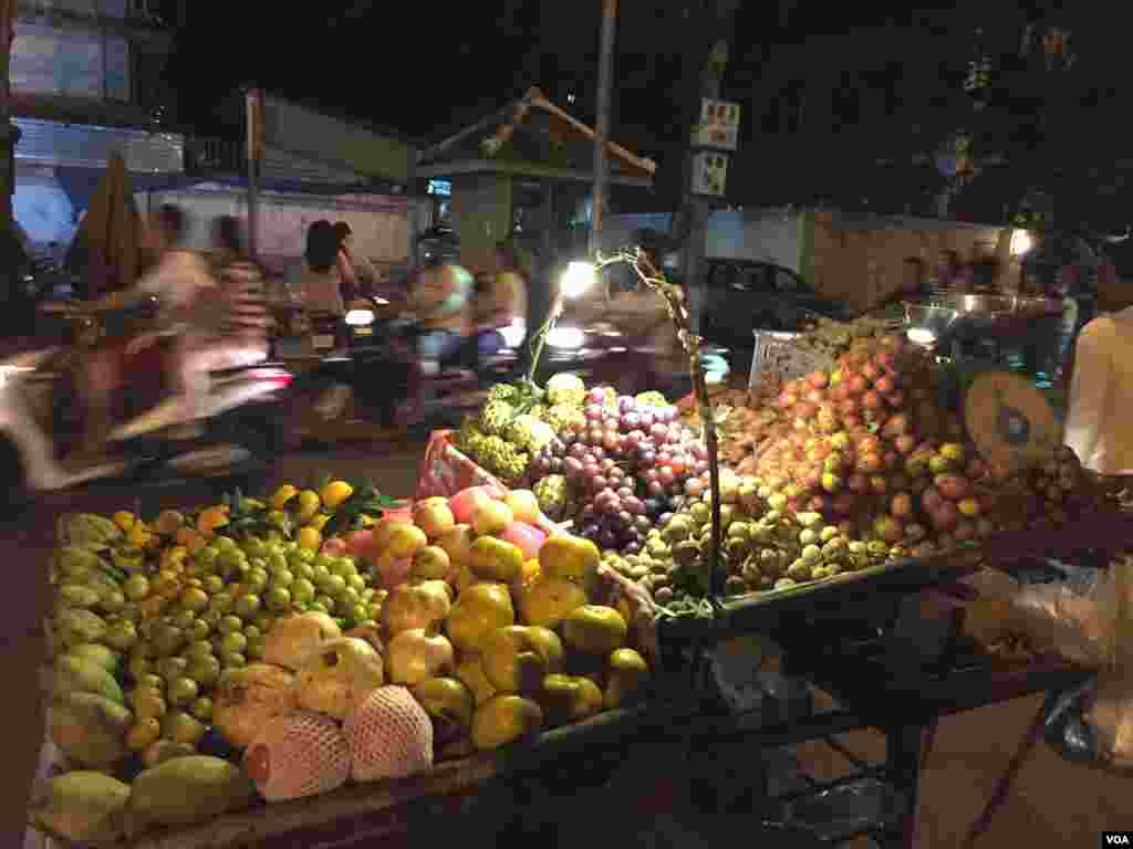 អ្នកដើរលេងជិះកាត់តូបលក់ផ្លែឈើនៅតាមផ្លូវជាប់របស់ព្រះបរមរាជវាំងកាលពីថ្ងៃទី២៦ ខែវិច្ឆិកា ឆ្នាំ២០១៥ ។ (ផន បុប្ផា/VOA)