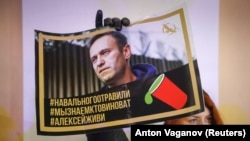 Ruska opozicionarka za slikom Alekseja Navaljnog u Sankt Peterburgu (Foto: REUTERS/Anton Vaganov)