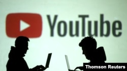 兩位使用移動設備的人士站在YouTube圖標投影前