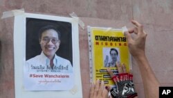 An activist pastes images of Thai dissident Wanchalearm Satsaksit on a wall near the Cambodian Embassy in Bangkok, Thailand, Monday, June 8, 2020. (AP Photo/Sakchai Lalit)