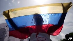 ARCHIVO - Un familiar de un preso en huelga de hambre sostiene una bandera venezolana durante una protesta en la avenida Bolívar en Caracas, Venezuela, el miércoles 12 de junio de 2024.