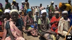 Sejumlah perempuan duduk di tanah, sedang mengantre untuk menerima makanan yang didistribusikan oleh Program Pangan Dunia (WFP) di Padeah, Sudan Selatan. (Foto: AP)