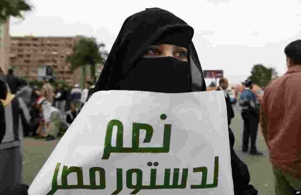 A supporter of Egyptian President Mohammed Morsi attends a rally in Cairo, Egypt, Dec. 14, 2012. Arabic on the poster at center reads, "yes to the Egyptian constitution."