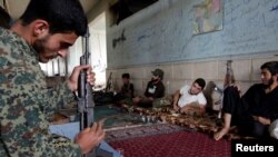 A rebel fighter from Jaysh al-Sunna, operating under a coalition of rebel groups called Jaish al-Fatah, or the army of conquest, prepares his weapon as others rest in Aziziyah village, southern Aleppo countryside, Syria, May 17, 2016. 