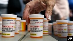 FILE -Family and friends who have lost loved ones to OxyContin and opioid overdoses leave pill bottles in protest outside the headquarters of Purdue Pharma, which is owned by the Sackler family, in Stamford, Conn., Aug. 17, 2018.