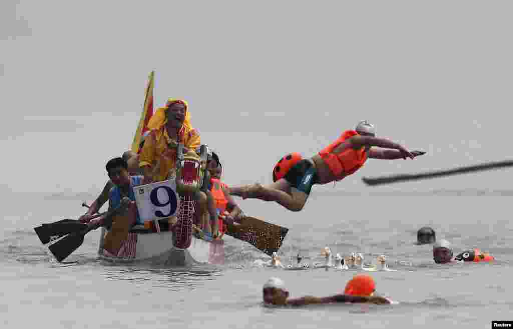 Peserta melompat ke sungai Yangtze untuk menangkat itik dan angsa sebagai bagian perayaan Festival Perahu Naga di kota Yibin, Sichuan, China.