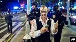 FILE - A reveler gets his picture taken by a friend in front of heavily armed police during the Greenwich Village Halloween Parade in New York. The NYPD says thousands of uniformed and plainclothes officers will patrol the 2018 parade in Greenwich Village