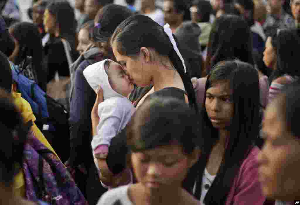 Seorang korban topan Haiyan yang selamat mencium bayinya sambil menunggu waktu naik ke pesawat evakuasi di bandara Tacloban, Filipina.