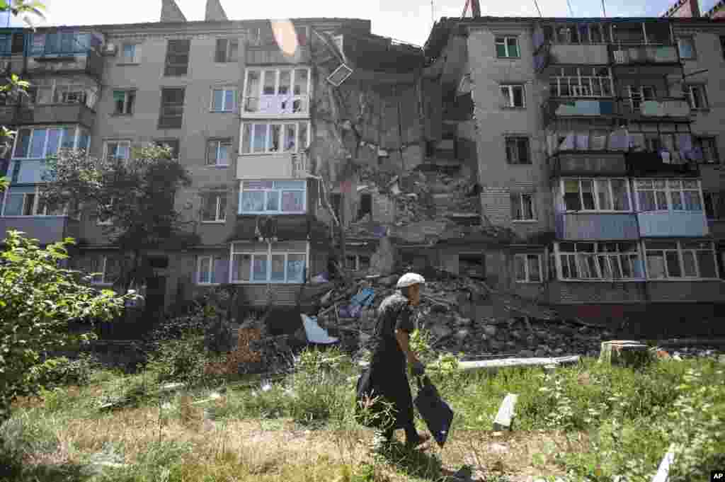 A woman walks past a building damaged by shelling in Slovyansk, eastern Ukraine, July 10, 2014.