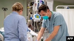 This US Navy handout photo obtained April 6, 2020 shows Lt. Wade Miller, from Orlando, Florida, treating a patient aboard the hospital ship USNS Mercy (T-AH 19)on April 4, 2020 in Los Angeles, California. - Mercy deployed in support of the nation's COVID-