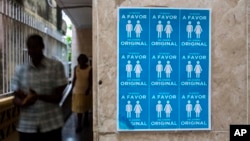 Cuban evangelists pass beside a poster in the Evangelist League Church that reads in Spanish, "I am in favor of the original design" in reference to discussions on same sex marriage to be included in new constitution in Havana, Cuba, Sunday, Oct. 7, 2018. (AP Photo/Desmond Boylan)