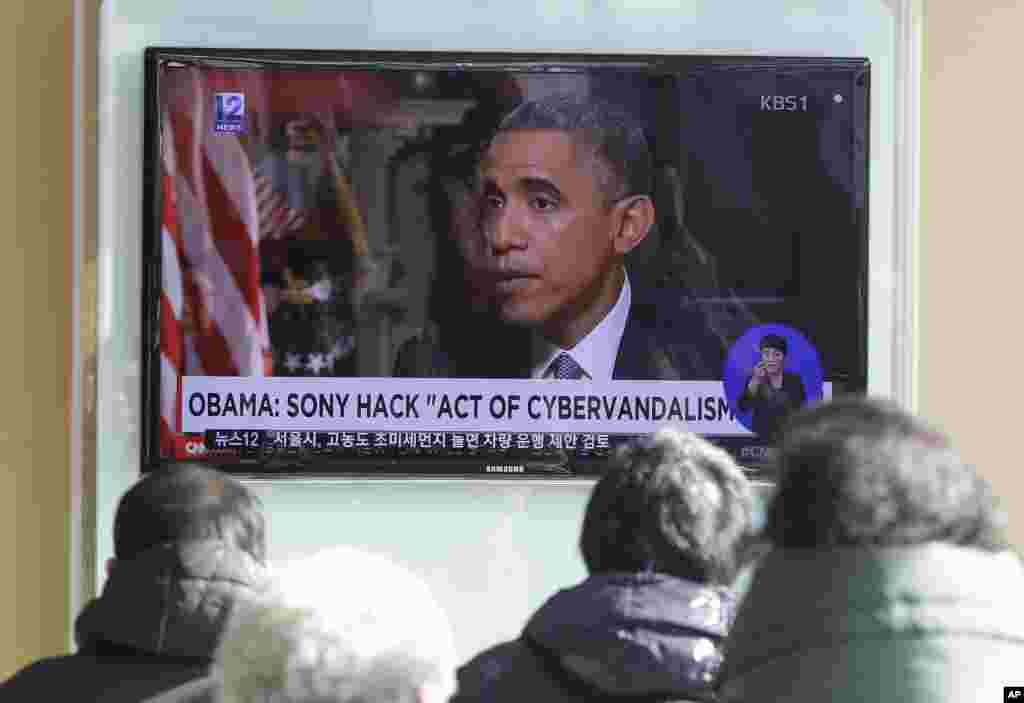 People watch a TV news program showing President Barack Obama, at the Seoul Railway Station in Seoul, South Korea, Dec. 22, 2014.
