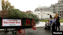 Ibu negara Michelle Obama dan dua keponakannya, Aaron dan Austin, menyambut datangnya pohon Natal di North Portico, Washington, 25 November 2016 (REUTERS/Gary Cameron )