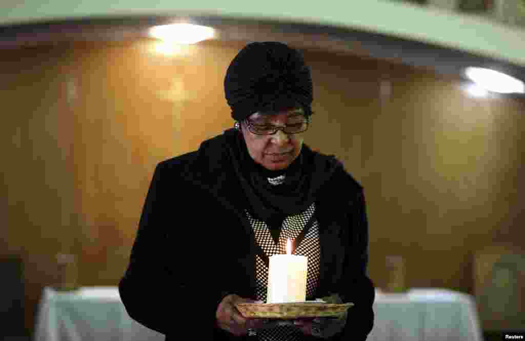 Winnie Madikizela-Mandela, ex-wife of former South African President Nelson Mandela, holds a candle during a prayer service for the ailing Mandela at a church in Johannesburg, July 5, 2013. 