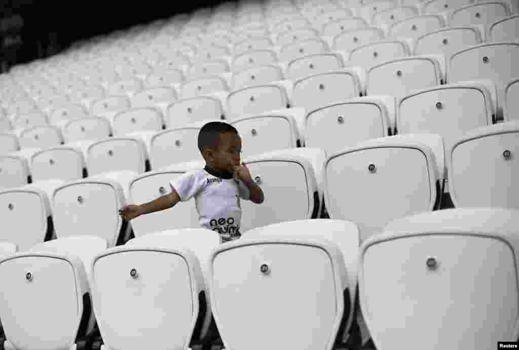 Uma criança, familiar de um funcionário, corre pelas bancadas, antes do início de um jogo entre funcionários do estádio para comemorar o dia do Trabalhador, na Arena de São Paulo, Maio 1, 2014.